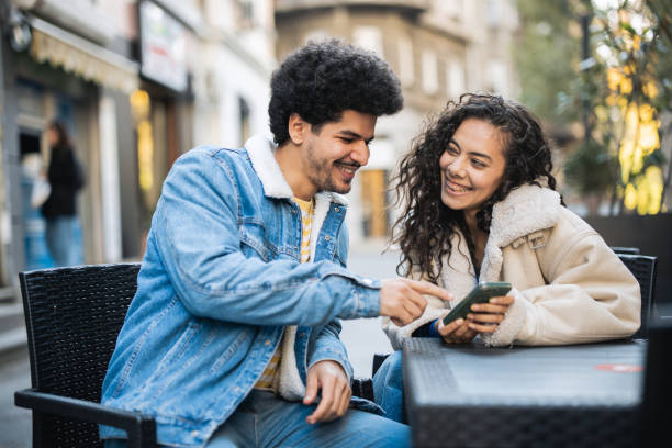 istock Middle Eastern couple relaxing at a cafe, sharing a moment while looking at a smartphone 2187223588