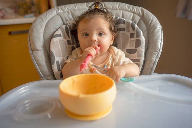 istock Adorable Baby Holding Spoon During Mealtime 2187229088
