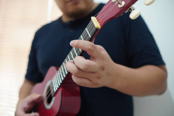 istock Asian man playing ukulele at home 2187229503