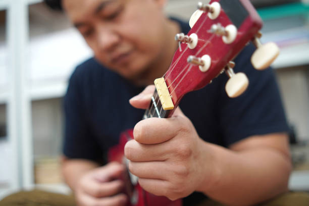 istock Asian man playing ukulele at home 2187229561