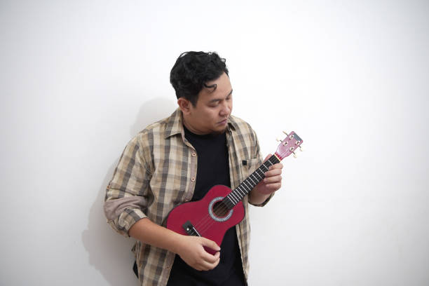 istock Asian man playing ukulele at home 2187230453