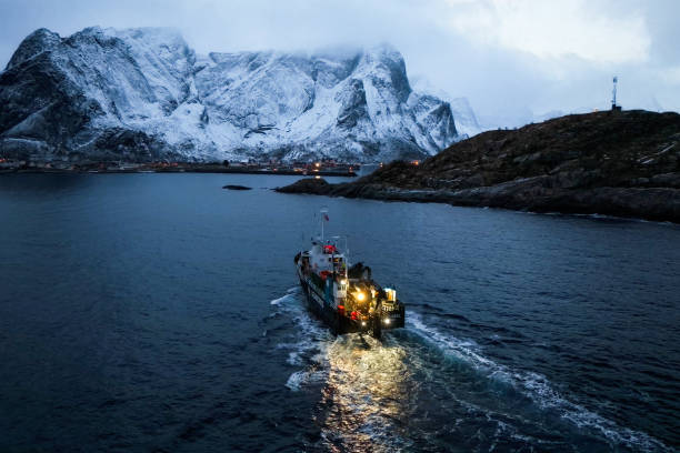 istock A fishing boat skillfully navigating through snowy waters surrounded by majestic mountains, 2187231126