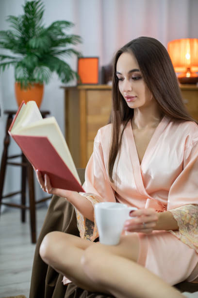 Indulging in a Cozy Reading Moment While Wearing a Soft Satin Robe and Sipping Coffee
