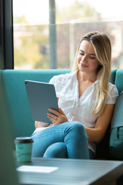istock Young Beautiful Blonde Woman Working on Digital Tablet in Modern Cafe Setting 2187232964