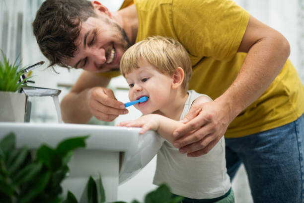 istock Little boy enjoying washing his teeth with dad. 2187237923