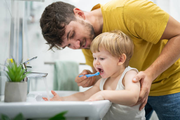 istock Little boy enjoying washing his teeth with dad. 2187237927