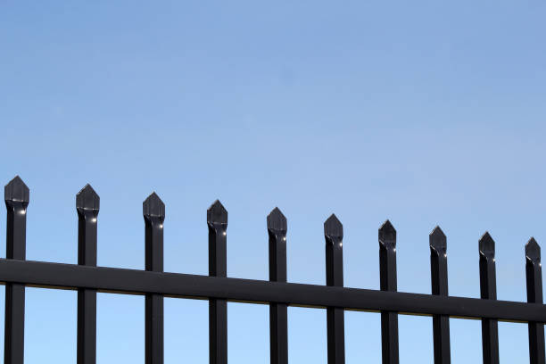 istock Black metal picket fence against a clear blue sky background 2187239947