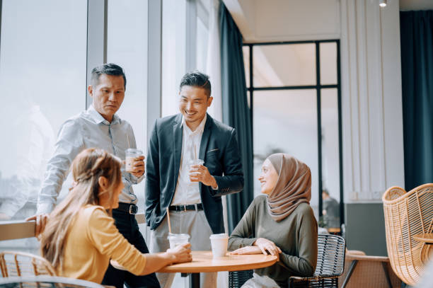Coffee break Asian white collar colleague discussion with window background