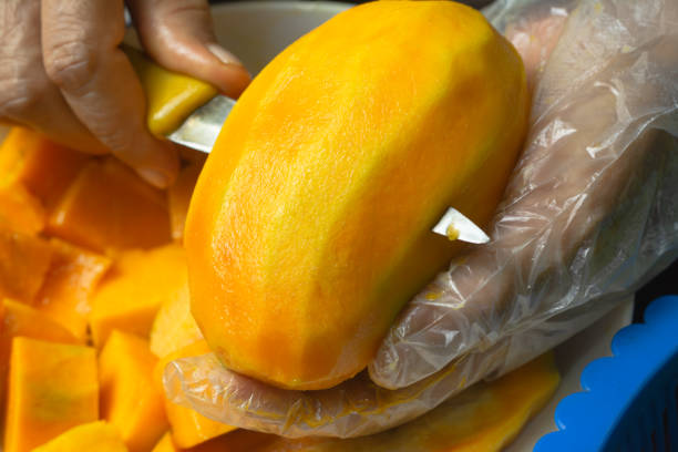 Close-Up Hands Slicing a Ripe Mango Fruit - Healthy and Fresh Snack Preparation