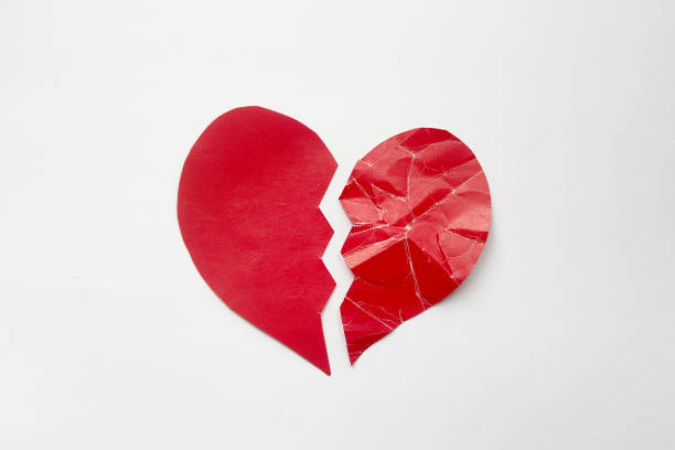 istock Paper red heart torn in half, one half crumpled symbolizing unrequited love. Broken heart isolated on white background 2187242818