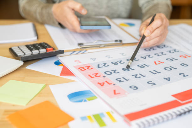 istock Businesswoman At Home Using Smartphone And Writing In Calendar For Event Planning, Scheduling, Organizing, Paying Bills, Deadlines, Goals, Time Management, Productivity, And Task Management. 2187248679