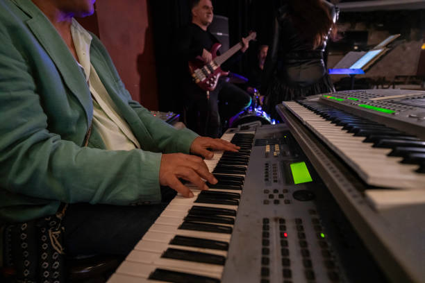 istock senior male keyboard player is practicing on stage at foreground bass player and female singer at background horiontal still 2187253654