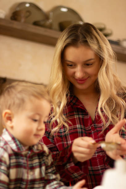 istock A mother with a one and a half year old child is preparing a festive dinner in the kitchen, dressed in checkered shirts, New Year's atmosphere 2187256508