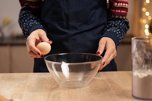 istock Woman hands are breaking egg for baking gingerbread cookies on the table in kitchen on Christmas Eve 2187262808