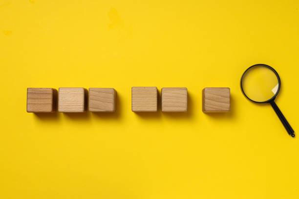 istock Lens and wooden cubes on yellow background, space for text 2187264407