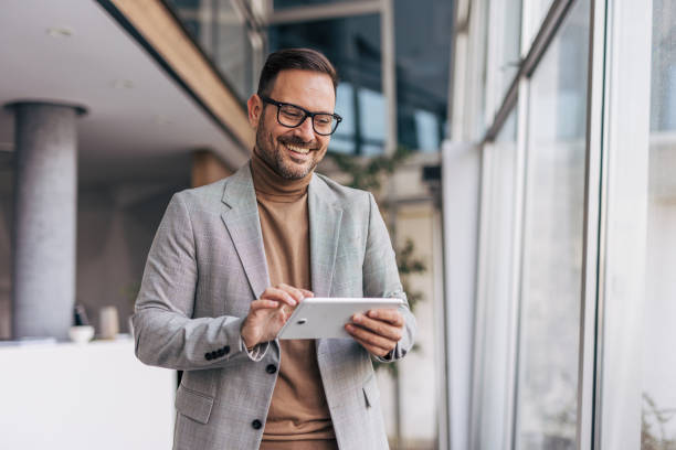 istock A smiling businessman is using a digital tablet while standing in an office corridor 2187264772