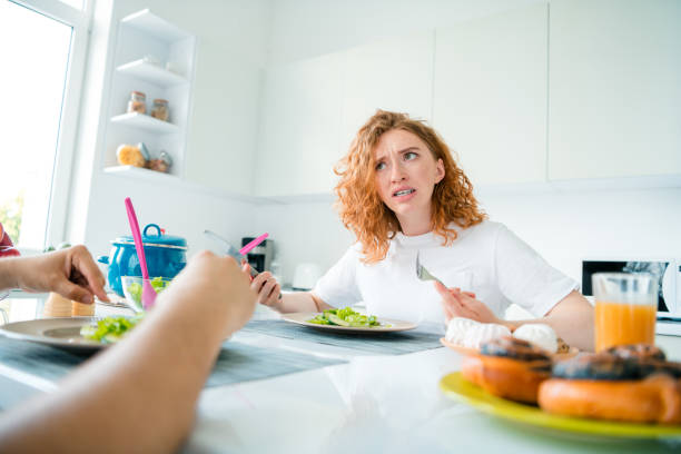 istock Young woman with red hair looking surprised while having meal in a bright kitchen during daylight 2187265166
