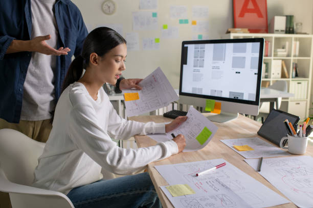 istock UX UI designers discussing and brainstorming on wireframes for a website and mobile app prototype, surrounded by sketches of user flow and design tools, in the concept of website and mobile application design concept. 2187265552