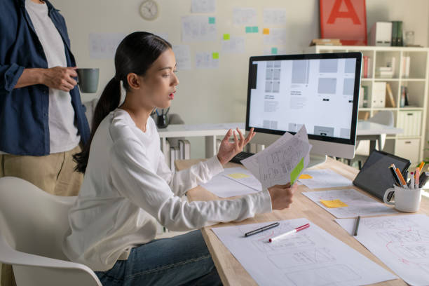 istock UX UI designers discussing and brainstorming on wireframes for a website and mobile app prototype, surrounded by sketches of user flow and design tools, in the concept of website and mobile application design concept. 2187265553