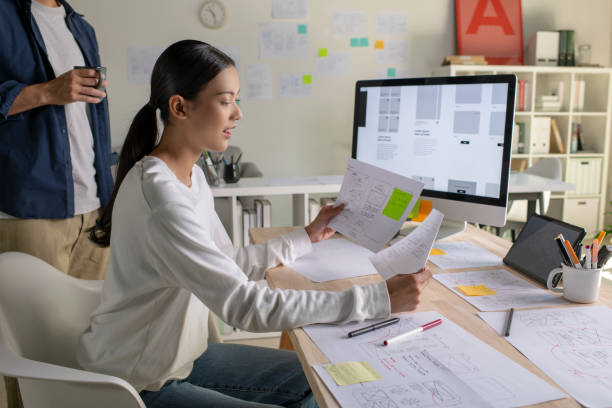 istock UX UI designers discussing and brainstorming on wireframes for a website and mobile app prototype, surrounded by sketches of user flow and design tools, in the concept of website and mobile application design concept. 2187265560
