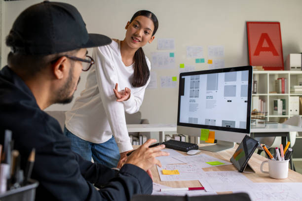 istock UX UI designers discussing and brainstorming on wireframes for a website and mobile app prototype, surrounded by sketches of user flow and design tools, in the concept of website and mobile application design concept. 2187265566
