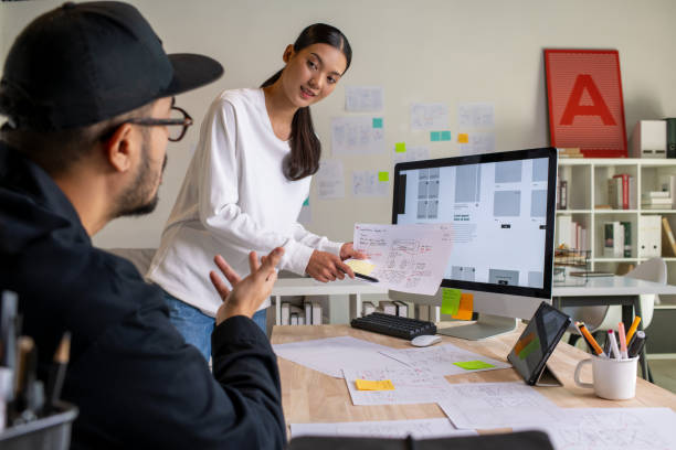 istock UX UI designers discussing and brainstorming on wireframes for a website and mobile app prototype, surrounded by sketches of user flow and design tools, in the concept of website and mobile application design concept. 2187265570