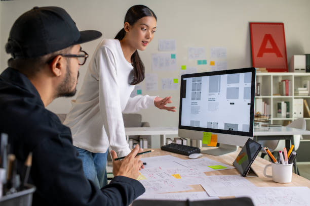 istock UX UI designers discussing and brainstorming on wireframes for a website and mobile app prototype, surrounded by sketches of user flow and design tools, in the concept of website and mobile application design concept. 2187265573