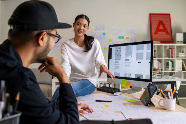 istock UX UI designers discussing and brainstorming on wireframes for a website and mobile app prototype, surrounded by sketches of user flow and design tools, in the concept of website and mobile application design concept. 2187265580
