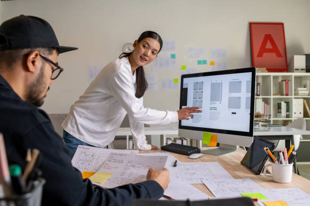 istock UX UI designers discussing and brainstorming on wireframes for a website and mobile app prototype, surrounded by sketches of user flow and design tools, in the concept of website and mobile application design concept. 2187265585