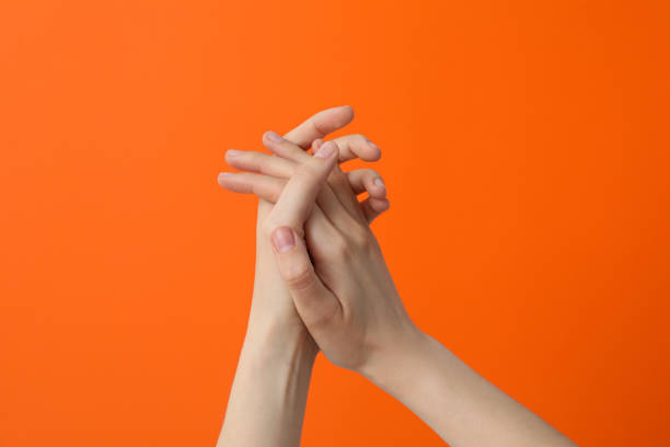 istock Two female hands clasped on an orange background 2187265845