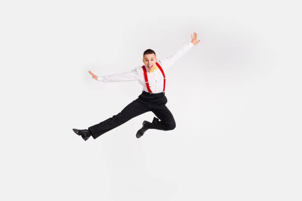 istock Dynamic man jumping energetically in elegant attire against a white background, showcasing vintage dance style with a happy expression 2187266295