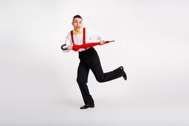 Handsome gentleman energetically dances with a bright umbrella, exuding happiness on a white background. His retro style and graceful movements capture the essence of dance and joy.