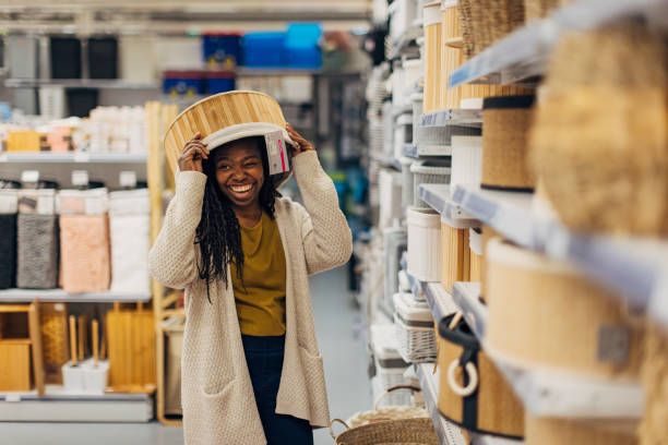 istock Black woman having fun shopping for storage baskets, placing one on her head 2187266975