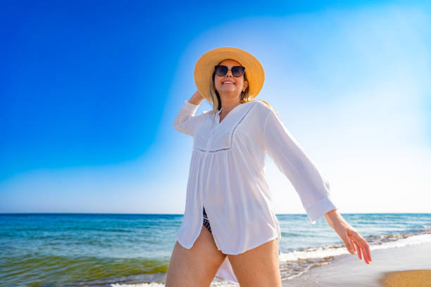 istock Beautiful mature woman walking on sandy beach. Front view 2187267382