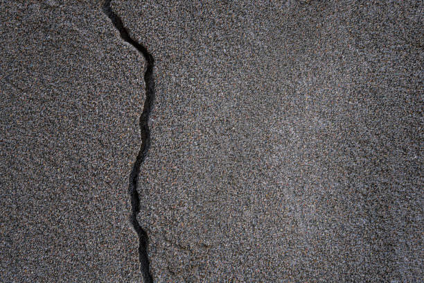 istock Textured background of concrete wall with deep dark crack in plaster. The surface is rough, with uneven lighting, with light areas in the middle, copy space, blank for art design 2187274361