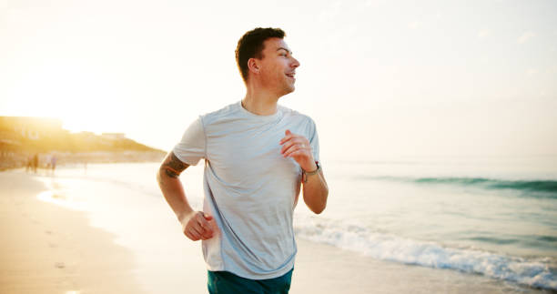 istock Fitness, man and running on beach for exercise, wellness and endurance training at space. Runner, cardio and happy athlete at ocean with energy, physical health and resilience at California seaside 2187274942