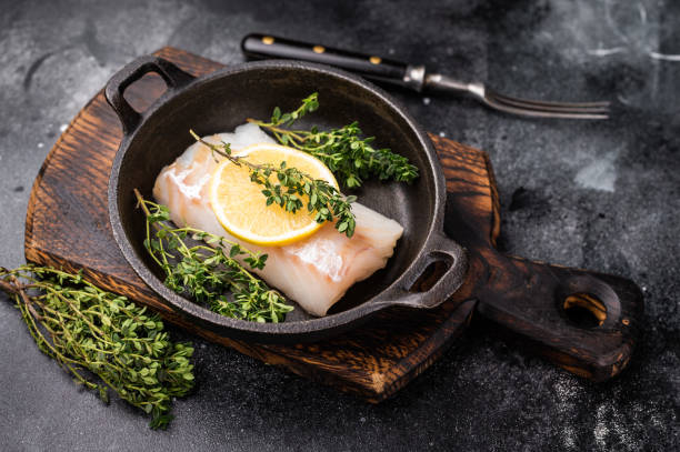 istock Raw cod fish fillets, whitefish without skin in skillet. black background. top view 2187275420