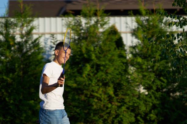 istock Boy playing badminton outdoors in a backyard with greenery during a sunny afternoon 2187277324