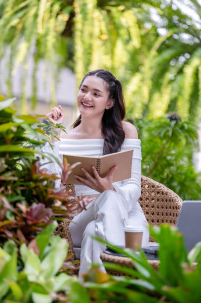 istock Young woman working remotely using a laptop and taking notes in a notebook Think and come up with project ideas in a relaxed atmosphere at an outdoor cafe. 2187277666