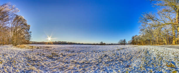 istock Snow-covered meadow with the sun rising, surrounded by trees, capturing a peaceful winter morning 2187279023