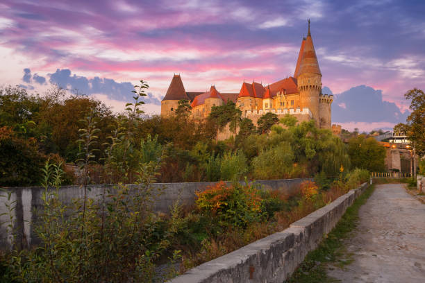 hunedoara, romania - 13 oct, 2019: corvin castle at sunrise. old fortress with tower. path through wonderful location in fall season