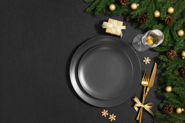 istock Beautiful Christmas table setting with black empty plate, gold accessories and fir branches on a black background with copy space. Top view, flat lay. 2187280519