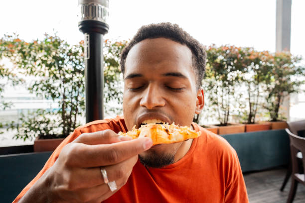 istock Young man eating pizza at restaurant 2187282751