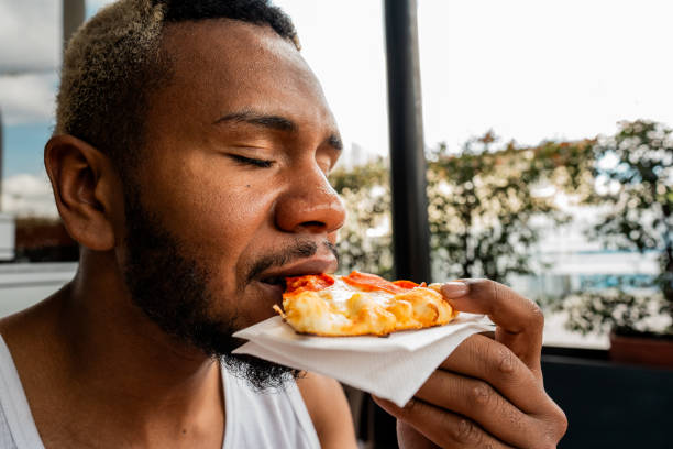 istock Young man eating pizza at restaurant 2187282753