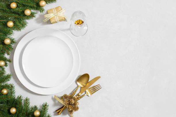 istock Empty white plate with golden cutlery, festive decor and fir branches on white background. Preparations for Christmas dinner. Copy space. Top view, flat lay. 2187282894