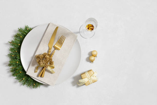 istock New Year or Christmas table setting with gold decorations and cutlery on white background with copy space. View from above. 2187283819