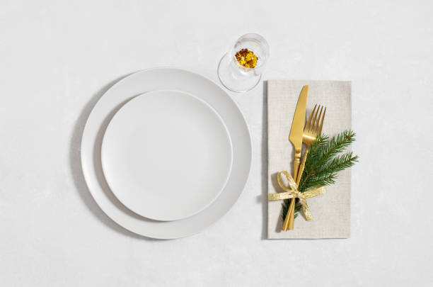 istock Beige empty plate with golden cutlery and a glass on white background. Christmas table setting. Happy new year. View from above. 2187284026