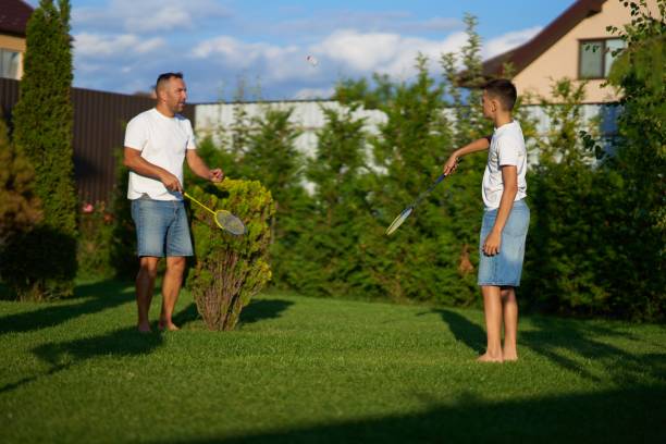 istock Father and son playing badminton together in a sunny backyard in summer 2187284536