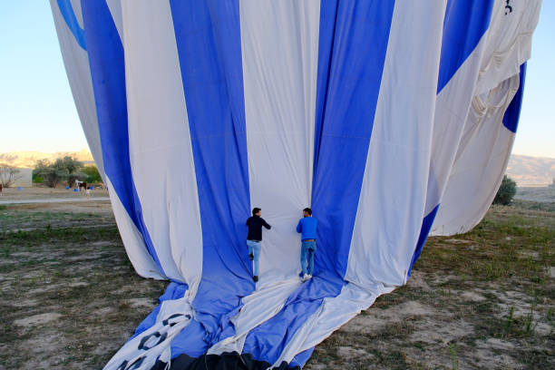 A unique inside perspective of a hot air balloon, showing the intricate design as it inflates, with people working in the background