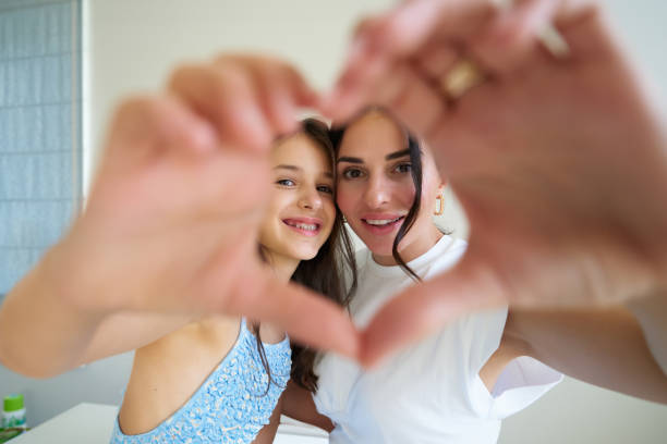 istock A mother and daughter making a heart shape with their hands while smiling at each other indoors 2187285059
